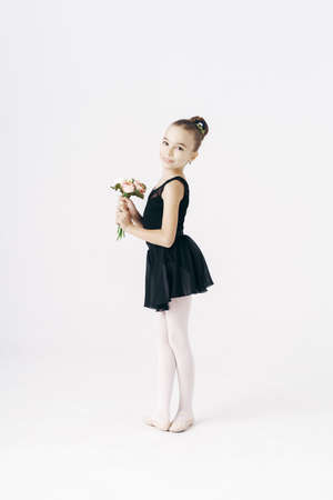 Beautiful girl ballerina dancing with flowers wearing a black tutu on white backgroundの写真素材