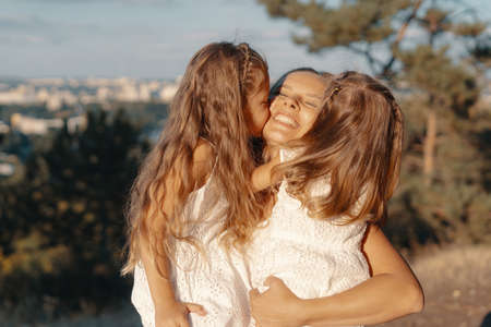A beautiful young woman playing with her daughter. happy family spends their day in the nature. Three blonde females, mother with her two little kids.の写真素材