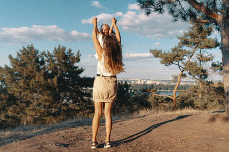 Joyfull young mother spend wonderful holiday time in the forest with her kid. Two blondies, mother...
