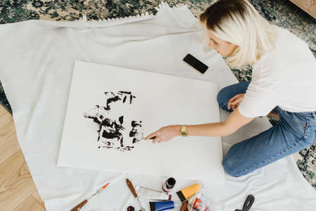 Beautiful young woman artist drawing in a comfy home interior