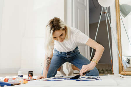 Beautiful young woman artist drawing in a comfy home interiorの写真素材