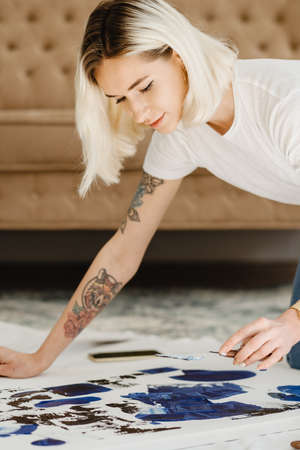 Beautiful young woman artist drawing in a comfy home interiorの写真素材