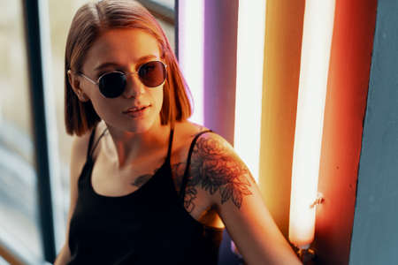 Fashion portrait of young attractive girl in sunglasses. Neon lightの写真素材
