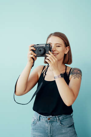 Stylish young girl photographer taking photos on blue backgroundの写真素材