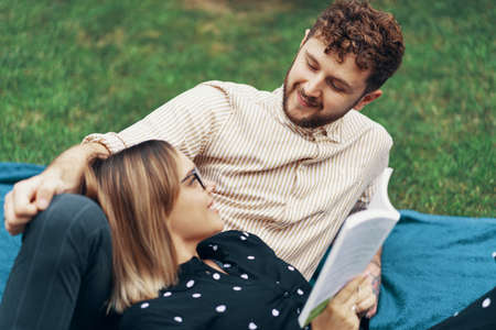 Couple in love lying on the grass in the yard of his house. Girl reading a bookの写真素材