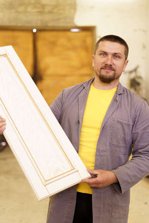 Skilled carpenter making furniture in workshop, fitting parts for wooden furniture. Profession...