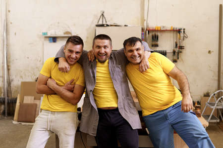 Smiling confident carpenters near their workbench in their workshop looking to cameraの写真素材