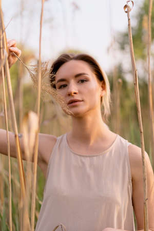 Young woman fashionable natural portrait in nature with sunlight on her faceの写真素材