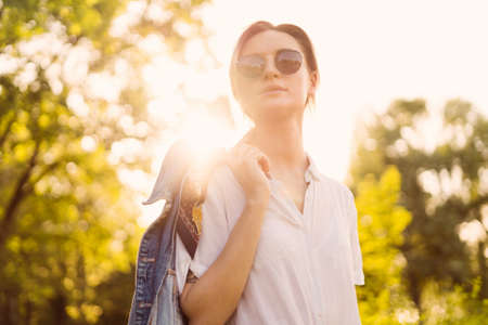 Joyful young woman in fashionable sunglasses walking in nature on a beautiful dayの写真素材