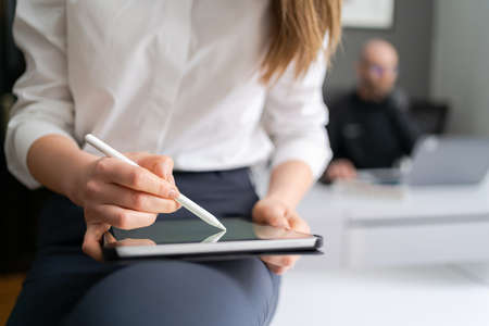 Business woman hands close up working with tablet in modern office wearing white shirt black pantsの写真素材