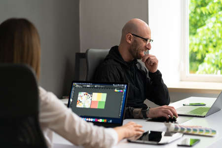 We already have great results. Young beautiful woman discussig something with her coworker while standing at office with laptopの写真素材