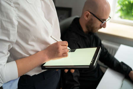 A woman working with color spectrum on a digital tablet while her work colleague working in parallel...