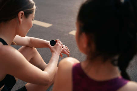 Women tracking time using arm watch. Her atractive friend waiting for results.の写真素材