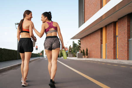 Young woman jogging on sidewalk in morning talking. Health conscious concept. Healthy active...