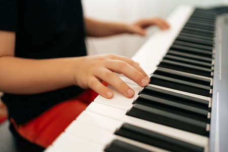 Close up young boy hands on digital piano. Playing keyboard, focused kid have activity at home....