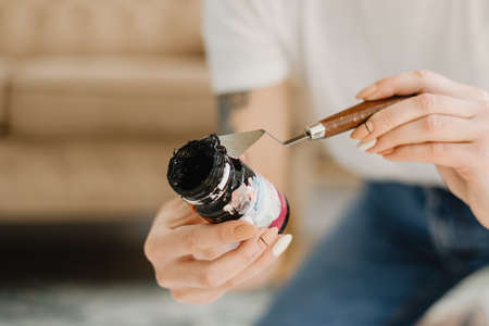 Cloaseup young woman artist holding black paint in her handの写真素材