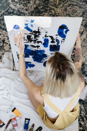 Beautiful young woman artist drawing in a comfy home interior