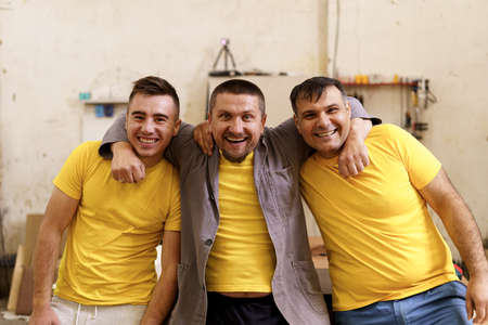 Smiling confident carpenters near their workbench in their workshop looking to cameraの写真素材