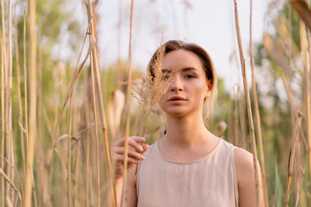 Young woman fashionable natural portrait in nature with sunlight on her face