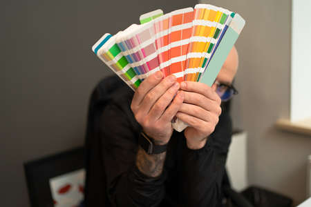 The color palette in the designers hands while working at his minimalist workplace in the modern officeの写真素材