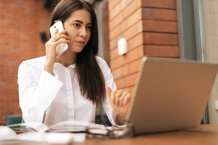 Corporate Communication. Caucasian Businesswoman Talking On Mobile Phone Working On Laptop In Modern...