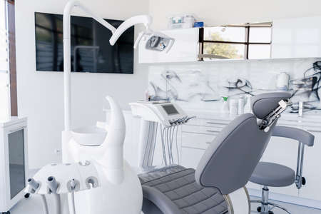 Interior of dental practice room with chair, lamp, display and stomatological toolsの写真素材