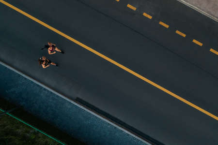 Runners running people fitness. Healthy active lifestyle. Active girls jogging together on road view from above. Summer weight loss training program.の販売画像