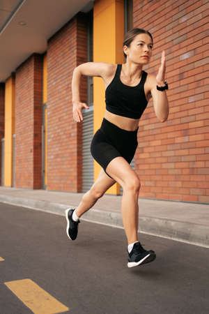 Young woman sprinting in the morning outdoors. Top view of female runner working out in the city.の写真素材