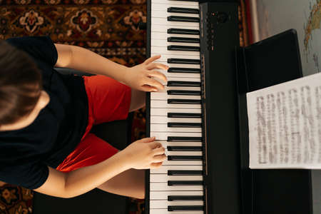 Young boy sitiing at digital piano. Playing keyboard, focused kid have activity at home. Hobby