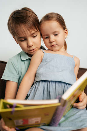 Bigger brother teaches his little sister to read while staying at home togetherの写真素材
