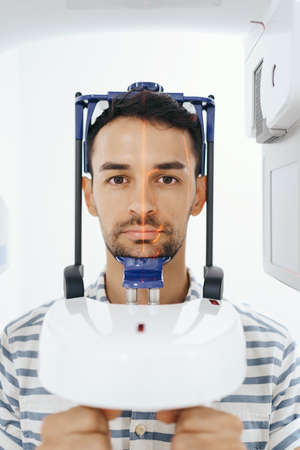Young man doing computer 3d tomography of teeth and jaw in modern dental clinic