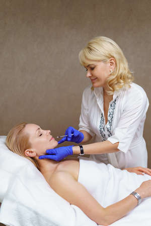 The doctor cosmetologist makes the Rejuvenating facial injections procedure for tightening and...