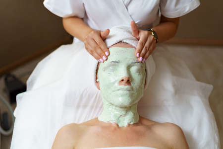 The process of removing the jellied alginate mask from the face of a woman. Facial rejuvenation procedure. Skin care in the beauty salonの写真素材