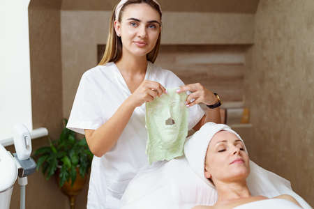 Beautician holds in her hands the shot alginate mask removed from customers face after skin rejuvenating procedure.の写真素材