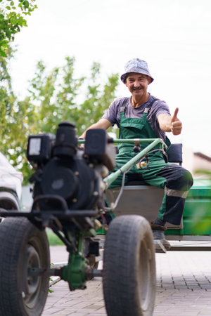 Satisfied farmer portrait sitting behind the wheel of a two-wheeled tractor.の写真素材
