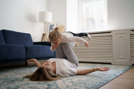 Young mother with little daughter practicing yoga at home. Family fizical activity, sporty mom and kidの写真素材