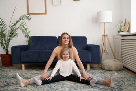 Young mother with little daughter practicing yoga at home. Family fizical activity, sporty mom and...