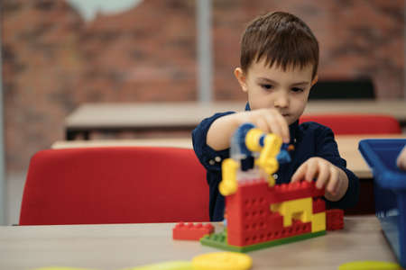 One kid choose parts of robotic electric toys for his age of four to build robots at robotics school lesson.の写真素材