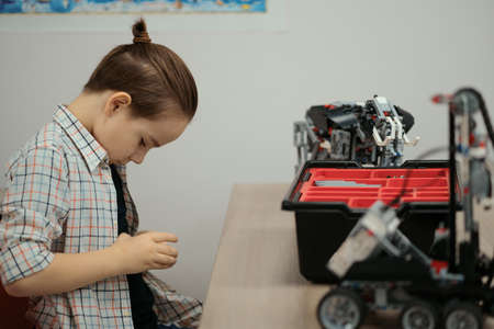 Boy Works on a Fully Functional Programable Robot for His School Robotics Club Project.
