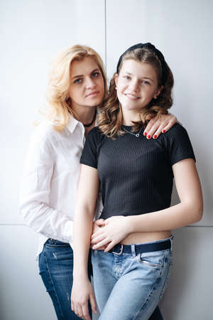 Beautiful mother and her pretty daughter teenager smiling and posing at home.