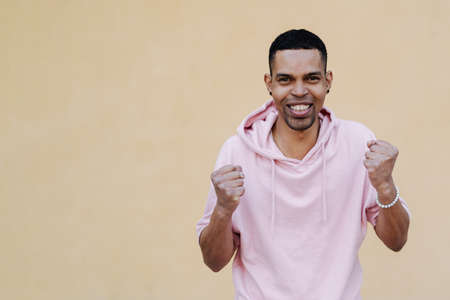 What a lucky guy I am. Shot of man who can not believe in his own happiness, being excited and feeling like on heaver from joy, holding hands on hair, surprised over yellow backgroundの写真素材