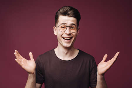 Image of satisfied smiling man in brown t-shirt, holding hands up in approval, recommend something...