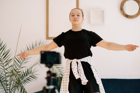 Online ballet classes, teacher explaining motion on camera screen. Young woman teaching ballet using a camera and tripod.の写真素材