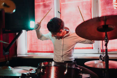 Male musician with drumsticks playing drums and cymbals at concert or studio. Music, people, musical...