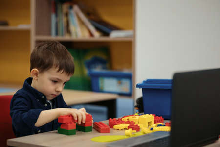 One kid choose parts of robotic electric toys for his age of four to build robots at robotics school lesson.の写真素材