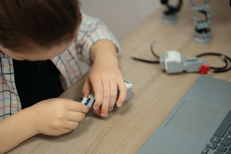 Boy using a laptop to program assembled robot from plastic bricks. STEM Education for kids.の写真素材
