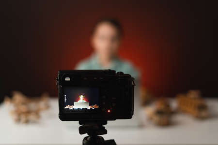 Kid blogger filming video on camera using the laptop, indoors. Online reviewing. Promoting eco...