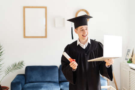Education, graduation and people concept - happy male student with diploma and laptop at home...