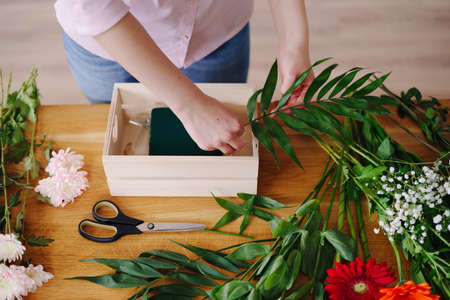 Florist at work: young woman hands making fashion modern composition of different flowers at home