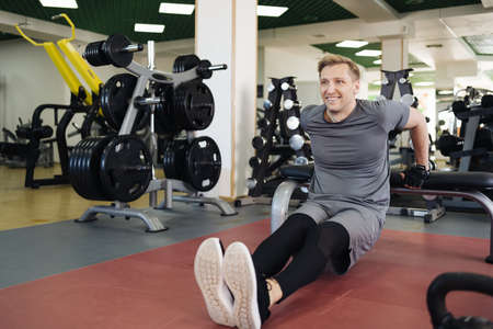 Athlete man in the gym doing elevations from floor. Caucasian male training in the gym during the...